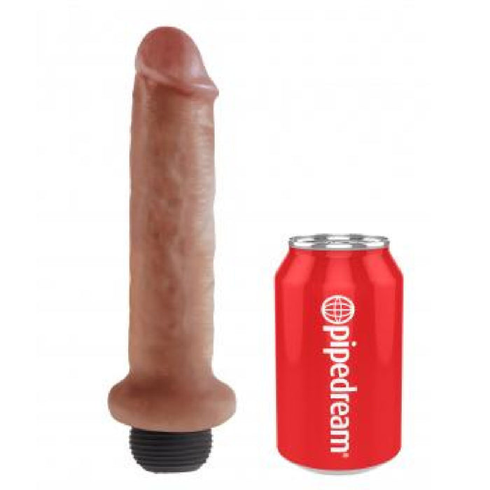 A caramel-colored, phallic-shaped object with a blush-colored tip stands vertical next to a red can labeled "Pipedream Products" in white text. The ultra-realistic King Cock Realistic Squirting 7 Inch Dildo - Caramel has veins and a dark base, offering an ideal size comparison with the beverage can.