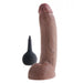 The King Cock Squirting 9 Inch Dildo with Balls - Chocolate by Pipedream Products, featuring a realistic, chocolate-toned design with a pronounced head and veiny details, stands upright next to a small black bulb enema in the background.