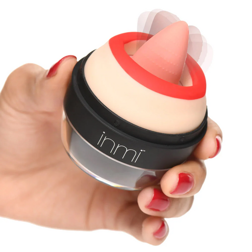 A hand with red nail polish holds a small, round device featuring a beige and red color scheme. The Lady Licker Rotating Tongue Stimulator with Discreet Case from XR Brands is crafted from premium silicone and showcases a pointed, raised tip at its center. Blurred lines suggest motion or vibration for oral stimulation. The word "inmi" is printed on the side of this waterproof device.