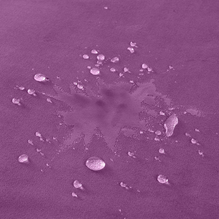 Sentence with the replaced product name and brand name: A purple-tinted image showing a Liberator Fascinator Throw Mini Sized Velvety Sex Blanket spill surrounded by smaller droplets on a moisture barrier surface, creating an abstract pattern.