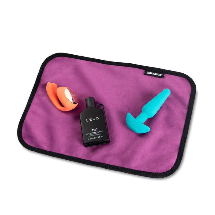 Liberator Fascinator Toy Pad Mini Waterproof Sex Blanket - Pink  with toys and lube on it 