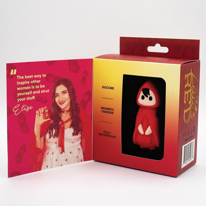 A boxed toy featuring a figure in a red hooded outfit. The box is partially open, revealing a photograph of a woman holding the Little Red First Time Discreet Powerful Bullet Vibrator by Natalie's Toy Box. Text on the box indicates that the discreet vibe is made of silicone, has a powerful motor with USB rechargeable capabilities, and is fully waterproof.