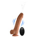 A photo of the Loadz 8.5 Inch Vibrating Squirting Dildo with Wireless Remote Control - Caramel from XR Brands shows the realistic-looking, flesh-toned dildo positioned upright, featuring a visible suction cup at its base and water squirting from its tip. Accompanying the dildo is a black wireless remote control complete with buttons and a logo. Wavy lines in the image illustrate its 10 modes of vibration.