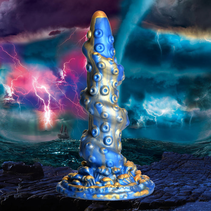 A tentacle-inspired sculpture in a stormy, oceanic setting. The piece, evocative of the Lord Kraken Blue and Gold 8.5 Inch Silicone Dildo by XR Brands, features a striking blue and gold color scheme adorned with suckers and intricate textured details. The background showcases dramatic clouds, lightning, and a ship navigating turbulent waves.