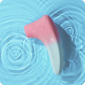 A pink and white handheld device, resembling a personal massager, is partially submerged in a light blue water surface. Water ripples surround the device, indicating movement. The smooth and curvy design of the Lovense Tenera 2 Bluetooth Clitoral Air Stimulator is accentuated by water droplets on its surface, hinting at superior clitoral stimulation.