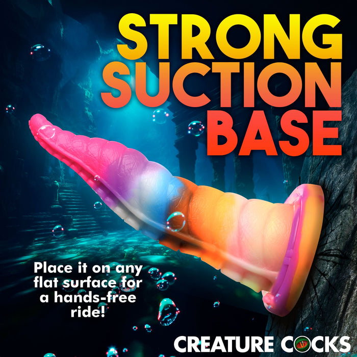 An image of a colorful, glow-in-the-dark tentacle-shaped toy with a strong suction base crafted from premium silicone. The text reads, "STRONG SUCTION BASE. Place it on any flat surface for a hands-free ride!" The background features an underwater scene with bubbles and stone pillars. The brand "XR Brands" is displayed at the bottom, showcasing the Luminoctopus Glow-in-the-Dark Tentacle Dildo.