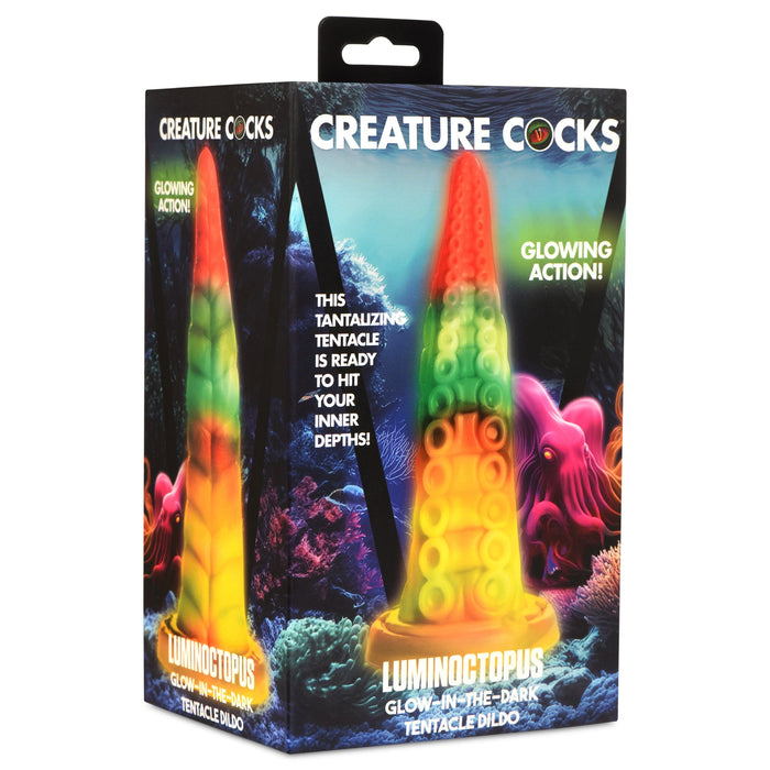 A colorful box featuring a glow-in-the-dark tentacle-shaped dildo. The packaging includes vibrant ocean-themed graphics with coral and sea life. Made from premium silicone, the text on the box identifies the product as "Luminoctopus Glow-in-the-Dark Tentacle Dildo" from "XR Brands," highlighting its glowing action.