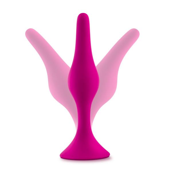 A magenta-colored anal plug from the Luxe Beginner 3 Plug Anal Trainer Set by Blush is displayed with its flaps in both open and closed positions to demonstrate its flexibility and functionality. The satin-smooth silicone exterior ensures maximum comfort, while the suction cup base provides stability. The background is white.