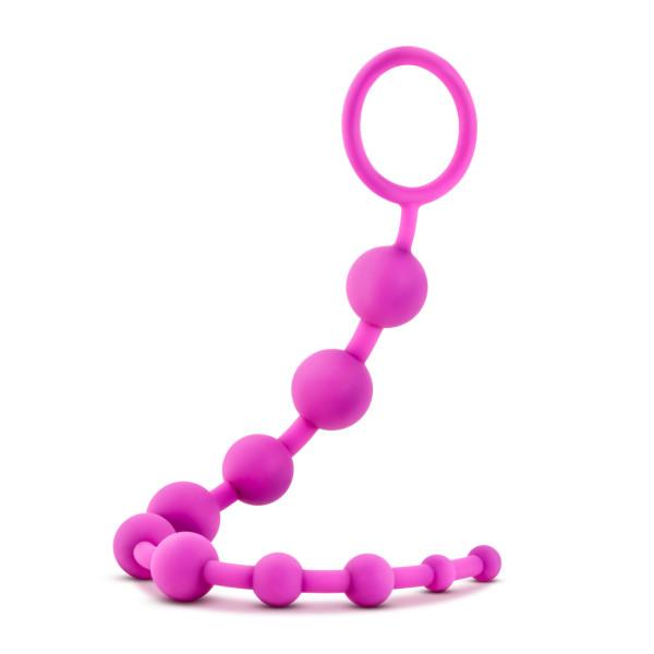 The Luxe Beginner Ultra Slim Silicone Anal Beads by Blush are body-safe and feature bright purple, linearly connected beads with a loop handle at the end. The beads range in size from small to large and can be bent to form a semi-circular shape.