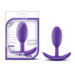 The image depicts the Luxe Medium Wearable Silicone Vibra Slim Plug - Purple in its packaging. The packaging from Blush emphasizes its wearability, pure silicone material, and powerful vibrations. The anal plug is shown next to the box, highlighting its anchor base for added comfort.