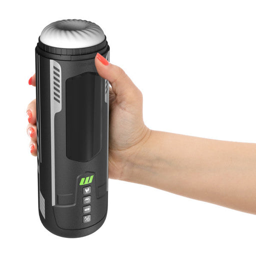 A person with red nail polish holds the sleek, black Master Blaster Vibrating, Stroking, Sucking, Warming, Automatic Stroker by Blush. The cylindrical gadget resembles a thermos and features buttons and a small screen near the bottom alongside a green logo. It utilizes cutting-edge suction technology and has a rounded top with a textured design for enhanced grip.