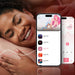 A smiling person with closed eyes rests their head on a pillow. In front of them are two smartphones displaying a music app; one shows a playlist with song titles and artwork, while the other shows a music player interface with playback controls. Nearby, the Honey Play Box Melody Pressure Sensing App-Controlled Wearable Vibrator adds to the scene's tranquility.