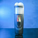 The Message in a Bottle Thrusting Spinning Stroker with Voices & Mount by Evolved Novelties is an electronic device with a cylindrical shape, featuring a digital screen and several buttons on the front. The top part has two round, smooth bulbs. This innovative stroker offers 7 speeds and functions. The background showcases a gradient of blue tones.