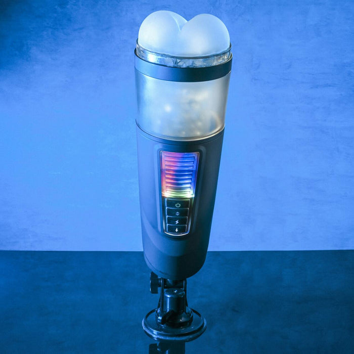 The Evolved Novelties Message in a Bottle Thrusting Spinning Stroker with Voices & Mount stands upright against a blue background, featuring a cylindrical shape. Its transparent top resembles two rounded peaks and it has colorful illuminated control buttons along the front. The base is equipped with a suction cup, offering 7 speeds and functions for versatile use.