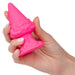 A hand holds the Naughty Bits Girthy Pink Gnome Butt Plug by CalExotics, a bright pink silicone object shaped like a small gnome figurine with a pointed hat, round face, and detailed body. The butt plug is small enough to fit comfortably in the palm of the hand.