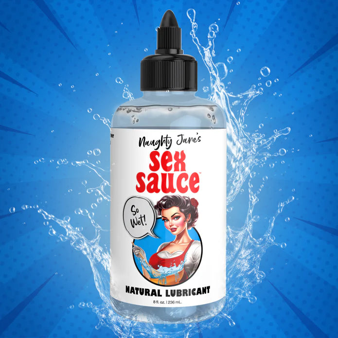 The photo showcases an 8oz bottle of Naughty Jane's Sex Sauce Natural Water Based Lubricant by XR Brands, with splashes of water surrounding it. The label displays a retro-style illustration of a woman holding a splash of water, accompanied by a speech bubble that says "So Wet!" against a blue, dotted background design.