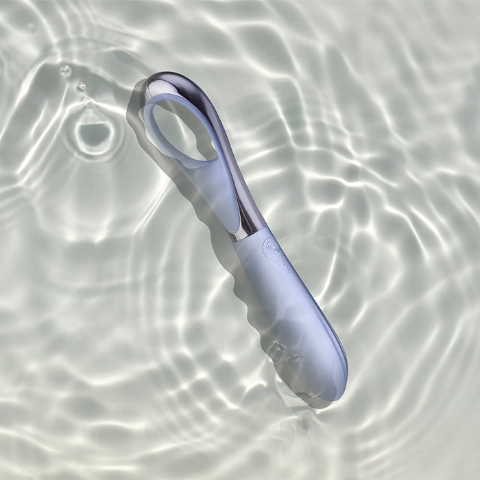 A sleek, modern Niya N3 Easy Grip Finger Loop Bullet Vibrator by Rocks Off with a smooth, ergonomic design floats in clear water with gentle ripples. The background features a light, wavy pattern created by the water's surface. With its waterproof and metallic glossy finish, this vibrator is both stylish and highly functional.