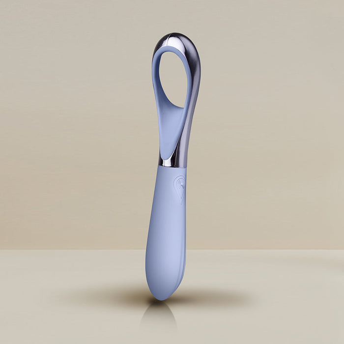 The Niya N3 Easy Grip Finger Loop Bullet Vibrator by Rocks Off features a sleek, modern design with a light blue silicone handle and a reflective metallic finger loop vibrator at the top. Specifically designed for clitoral stimulation, this waterproof device stands upright against a neutral beige background.