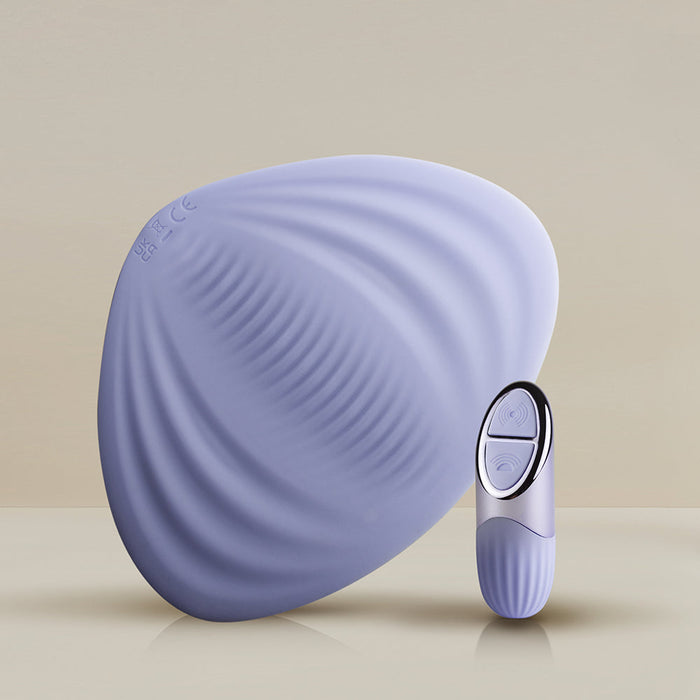 The Niya N5 Flexible Lay On Humping Vibrator from Rocks Off, in a soothing lavender shade, is featured alongside its matching, sleekly designed remote control with two buttons. The waterproof vibrator has a textured surface with subtle ridges, while the control unit boasts a shiny finish. Both items are set against a neutral background.