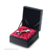 The sleek, silver Njoy Pure Small Stainless Steel Butt Plug with Loop Handle, crafted from 316 Grade Hand Polished Stainless Steel, is displayed inside a black, open gift box. The toy rests on a cushioned red satin interior. Its curved design with bulbous ends of different sizes showcases the elegance and allure of Njoy's Pure Plugs line.