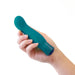 A person's hand holding the Blush Oh My Gem Fierce Blue Topaz Warming G-Spot Vibrator, which is a small, silicone phthalate-free miniature vibe with a curved, rounded tip and a transparent base, against a white background.