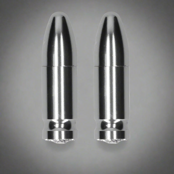 Two shiny, black-and-silver bullet-shaped objects stand upright against a plain white background. The items resemble bullet casings but may not be firearms-related. Their smooth, silver-plated surfaces reflect light, suggesting they could be powerful magnets or perhaps something entirely different. They are the Ouch! Diamond Tipped Bullet Magnetic Nipple Clamps - Gold from the brand Shots.