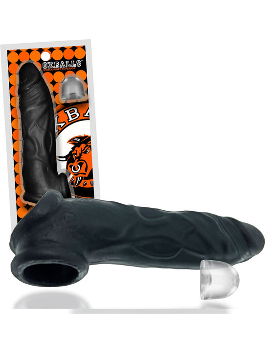 A black textured silicone sleeve for enhancing sexual pleasure is showcased outside its packaging. The packaging, featuring bold orange graphics with the brand name "Oxballs," includes an image of the Oxballs Dicker 7.5 Inch Cock Sheath - Black Ice made from durable Plus+SILICONE. A small, clear attachment is also displayed.