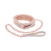 The Peaches 'n Cream Fur Collar and Leash by Sportsheets features a plush pink collar with a soft interior, accented by a rose gold chain link leash. This set is ideal for intimate moments, complete with a white looped handle on the leash and a buckle fastening on the collar.