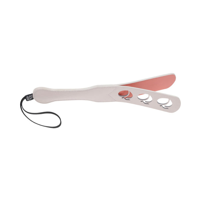 The Peaches 'n Cream Impression Paddle by Sportsheets is a two-toned faux leather paddle featuring a handle and wrist strap. It has three circular cut-outs near the end, making it ideal for varied impact and creating an intricate design during impact play.