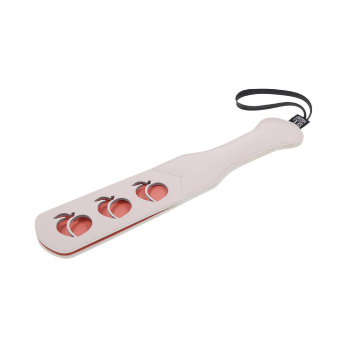 The Sportsheets Peaches 'n Cream Impression Paddle features a sleek white design with a black faux leather handle and a secure wrist strap. It includes three distinct peach-shaped cutouts, making it ideal for impact play enthusiasts who appreciate both style and function.