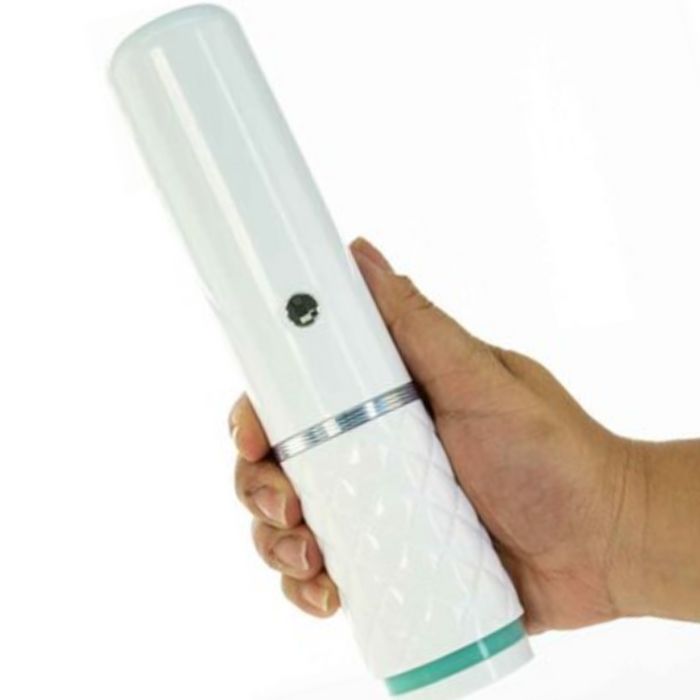 A hand is holding the Pillow Talk Feisty Thrusting Vibrator with Case by BMS Enterprises, a white cylindrical device with a textured shaft and a green ring near the base. The USB rechargeable vibrator features a single button and appears to be made of plastic. The background is plain and white.