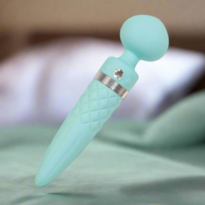 The Pillow Talk Sultry Warming Double Ended Wand Vibrator by BMS Enterprises in teal is a personal massager with powerful vibrations and a textured grip resembling an ice cream cone. Crafted from premium silicone, it features a rounded head and a pointed end, with a metallic accent near the top. The surface includes a quilted design for easy handling.