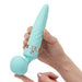 A person holding the Pillow Talk Sultry Warming Double Ended Wand Vibrator by BMS Enterprises, which boasts a quilted handle and a sleek, tapered end on one side with a round, bulbous head on the other. The teal-colored toy is crafted from premium silicone and features a metallic band near its base while adjustments are being made by the person's hands.