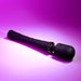 A Playboy Royal Rechargeable Black Silicone Wand Vibrator from Evolved Novelties, featuring a slim, textured handle and a rounded head, is placed on a pink and purple gradient background. The wand massager showcases a shiny, metallic ring near the head, adding a sleek and modern touch to its design.