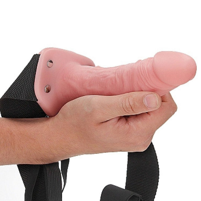 Vanilla Realrock 6 Inch Hollow Dildo & Strap-on Harness  being held by a hand on a white background