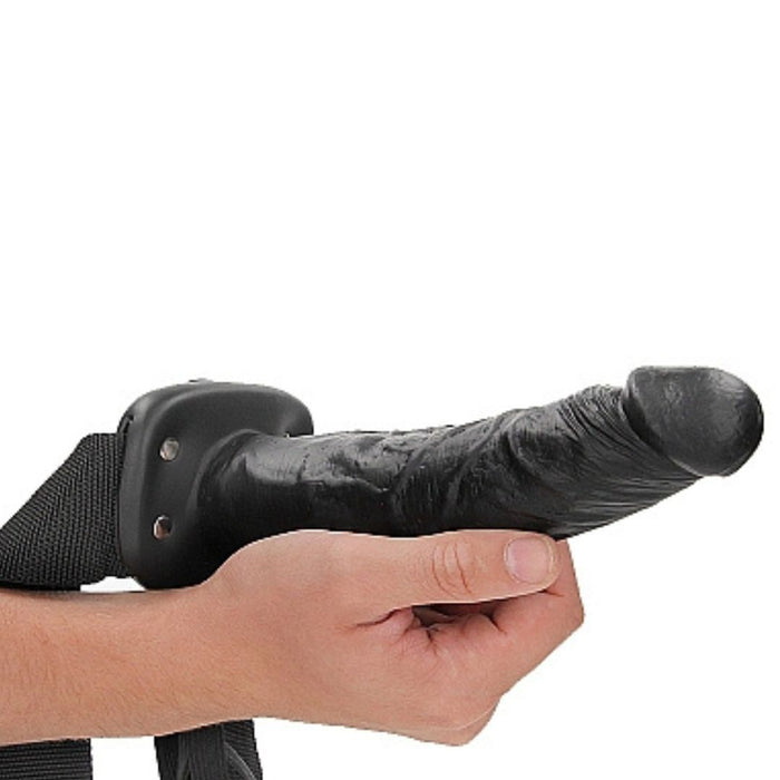 Black Realrock 8 Inch Hollow Dildo & Strap-on Harness being held by a hand on a white background