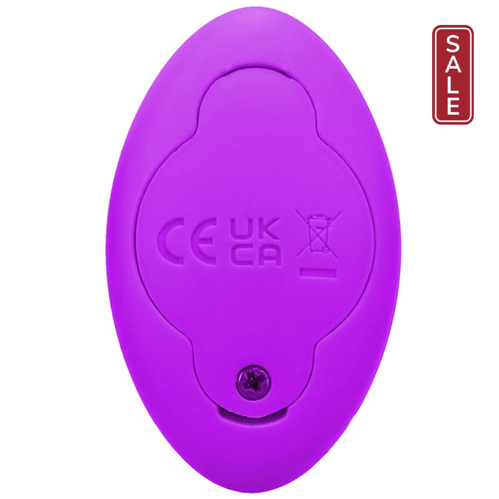 A close-up of the Remote Controlled Panty Vibrator for Beginners in a Bag by Doc Johnson, showcasing its small, oval-shaped purple design and regulatory compliance symbols on its backside, including CE and UKCA markings along with a crossed-out wheeled bin icon. A screw at the bottom highlights its eco-friendly assembly.