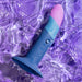 Colorful Lovehoney Romp Piccolo First Time Pegging Kit - Strap on Harness + Dildo partially submerged in water with swirling purple hues around it, reflecting shimmering light.