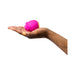 A hand with orange-painted nails is holding a small, pink WOW Romp Rose Pleasure Air Clitoris Stimulator against a plain white background. The hand is slightly cupped, prominently displaying the rose-shaped silicone-coated toy.