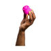 A hand with painted nails holds a small, pink, rose-shaped object against a white background—the Romp Rose Pleasure Air Clitoris Stimulator by WOW, designed to harness Pleasure Air Technology for an unparalleled experience.