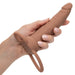 A hand with light pink manicured nails holds the Performance Maxx Double Penetration Vibrating Dildo in light chocolate, featuring a realistic texture, a round base with two loops, and ideal for anal exploration.