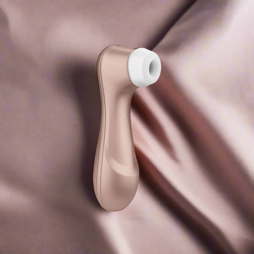 The Satisfyer Pro 2 Waterproof Pressure Wave Clitoral Stimulator by Satisfyer is a rose gold, handheld massager featuring a white attachment at one end, specifically designed for targeted clitoris stimulation using pressure waves. Its sleek, ergonomic design ensures comfortable handling and the device stands upright on its end, displaying its modern aesthetic.