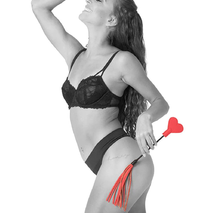 Side view of model holding Sex & Mischief Amor Red Heart Crop and Flogger