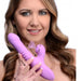 A person with long hair is holding the Shegasm Thrusting & Clitoral Air Pulsation Rabbit Vibrator – Purple by XR Brands. Designed for both internal and external stimulation, this luxury toy features thrusting vibration, a clitoral stimulator, a curved shape, ribbed detailing on the shaft, and a smaller protrusion. Arrows in the image highlight its various features.