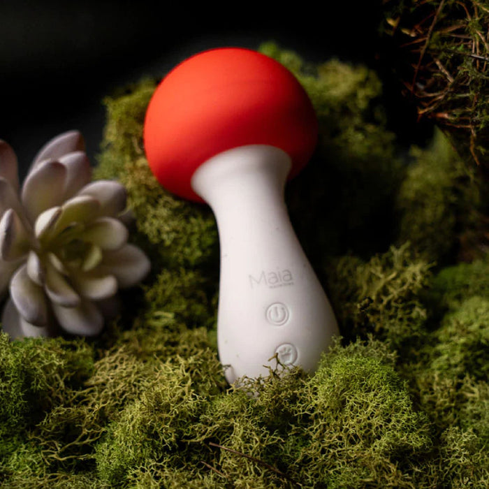 A captivating white and red object, featuring a red ball on moss, reminiscent of Trippy Toys, is the Shroomie Mushroom Shaped Mini Wand Vibrator by Maia Toys.