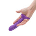 A hand holding the Simple and True Silicone G-Spot Finger Extender by BMS Enterprises, a purple, curved personal massager featuring textured ridges on the underside. The device is ergonomically designed for targeted G-spot stimulation.