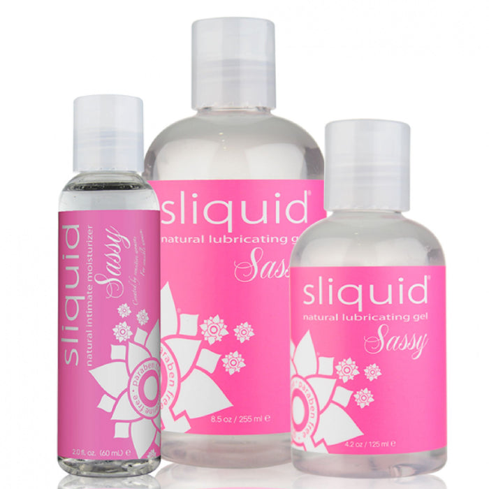 Three bottles of Sliquid Naturals Sassy Water Based Anal Lubricant from the brand Sliquid are shown in various sizes. The clear bottles with pink labels feature white text and floral designs. Ranging from 2 to 8.5 ounces, this glycerin-free product is also hypoallergenic for sensitive users.