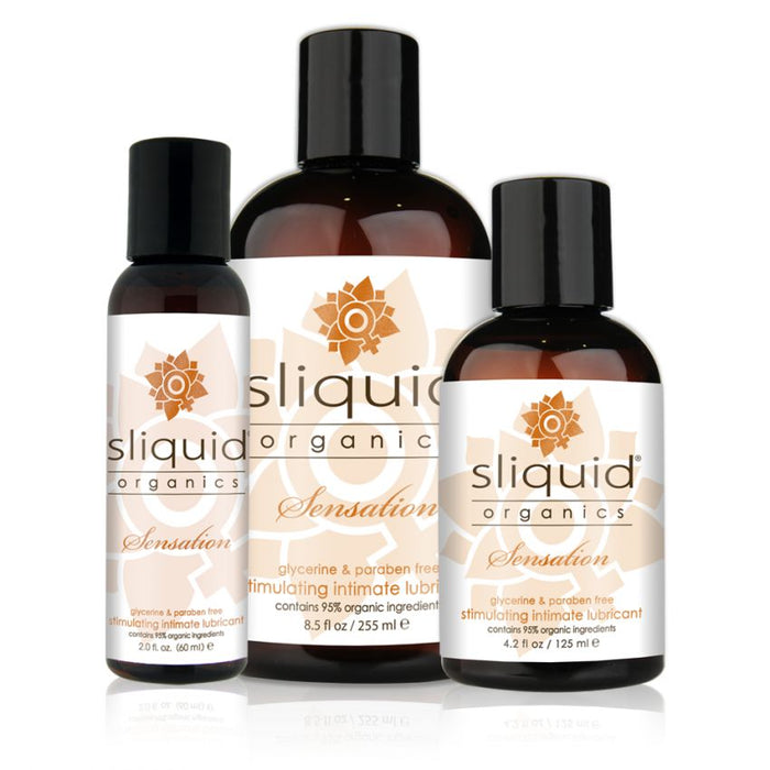 Three bottles of Sliquid Organics Sensations Stimulating Lubricant in various sizes are displayed in increasing order from left to right. The dark brown bottles showcase a white and beige design, prominently featuring the brand name "Sliquid" along with the product name, emphasizing their organic and vegan-friendly ingredients.