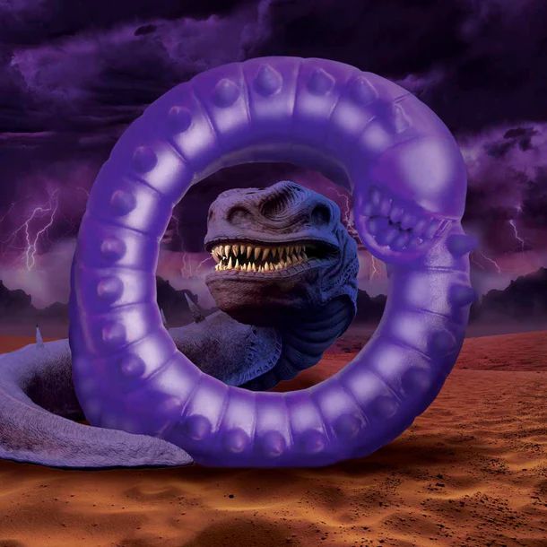 A surreal creature with a snake-like body and a dinosaur head is enclosed within the glowing XR Brands Slitherine Snake Fantasy Cock Ring. The background features a dramatic, stormy sky with lightning and ominous clouds over a barren, reddish landscape.