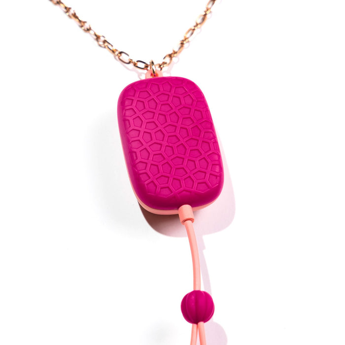 The Sphinx Bluetooth App-controlled Vibrating Nipple Clamps feature a pink, geometric-patterned pendant on a rose gold chain with a dangling cord and bead, offering a modern design that stands out against the white background.